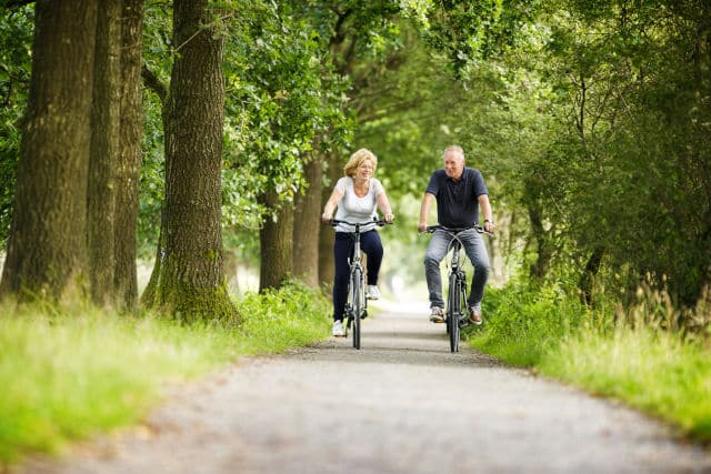 Twee personen fietsen door het bos.